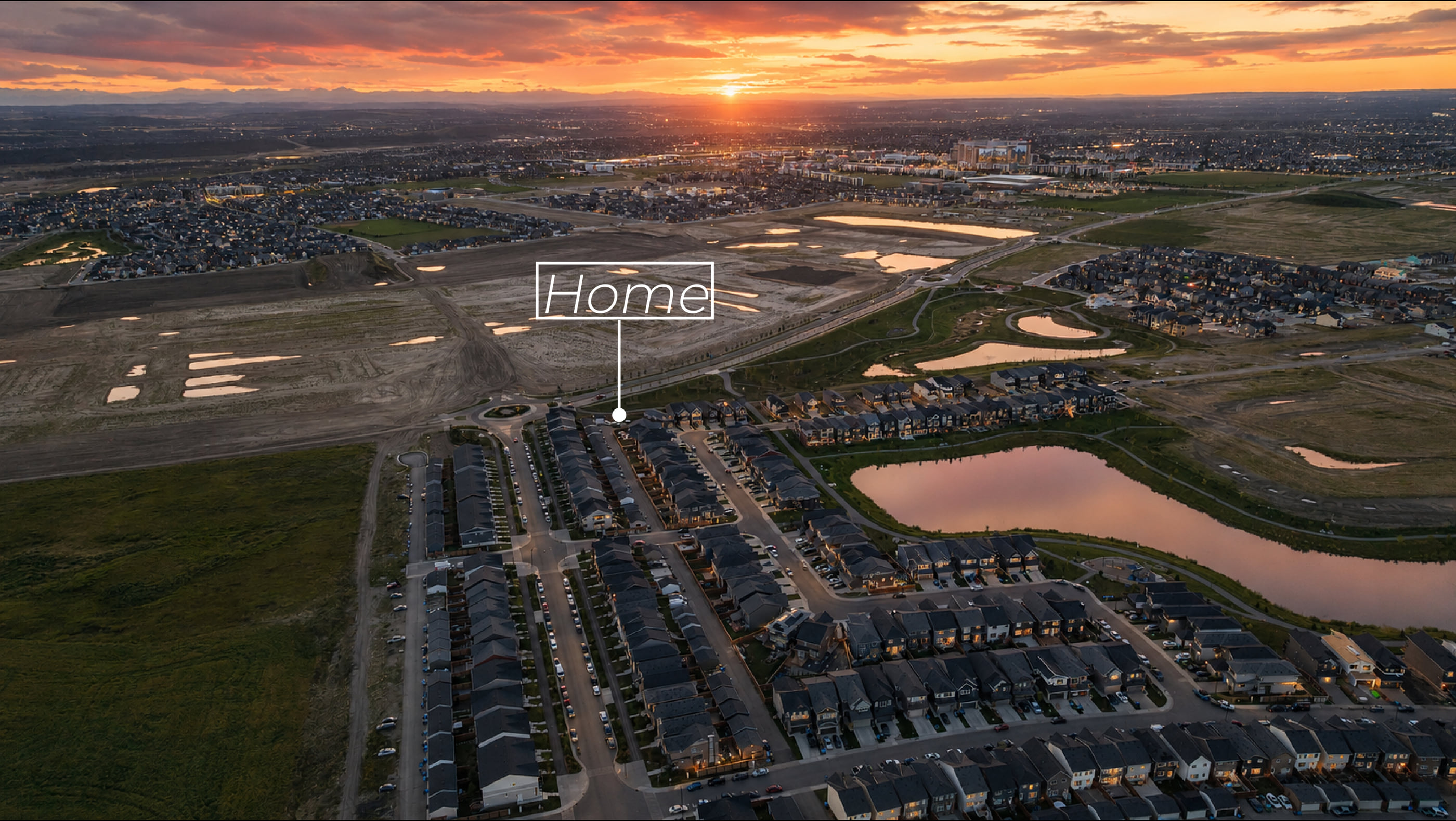 Rangeview from the air at sunset, with 215 Mallard Grove marked, the pond behind it and the lights of Seton on the horizon